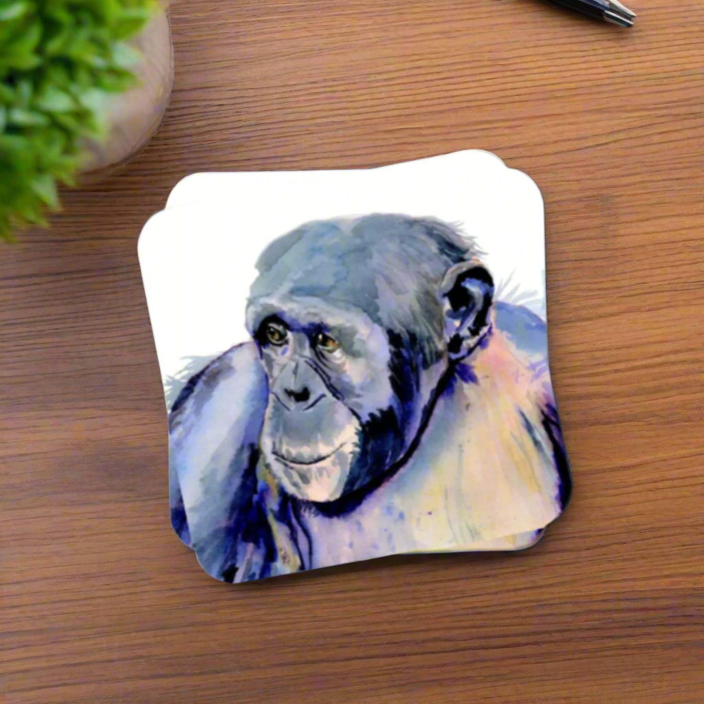 "A square glossy coaster on a wooden surface, featuring a print of an original watercolour painting by artist Jagos Art. The artwork depicts a chimpanzee gazing to the side with a soulful expression, painted in purple hues."