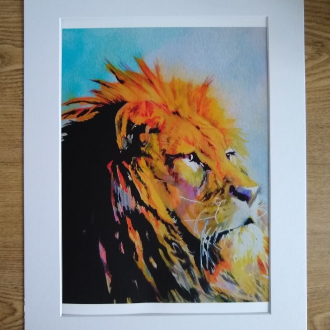 "An A4 art print, in a white mount, featuring an original watercolour painting by artist Jagos Art. The artwork showcases a majestic lion with a golden mane, gazing into the distance with strength and wisdom. Printed on archival paper for lasting vibrancy."