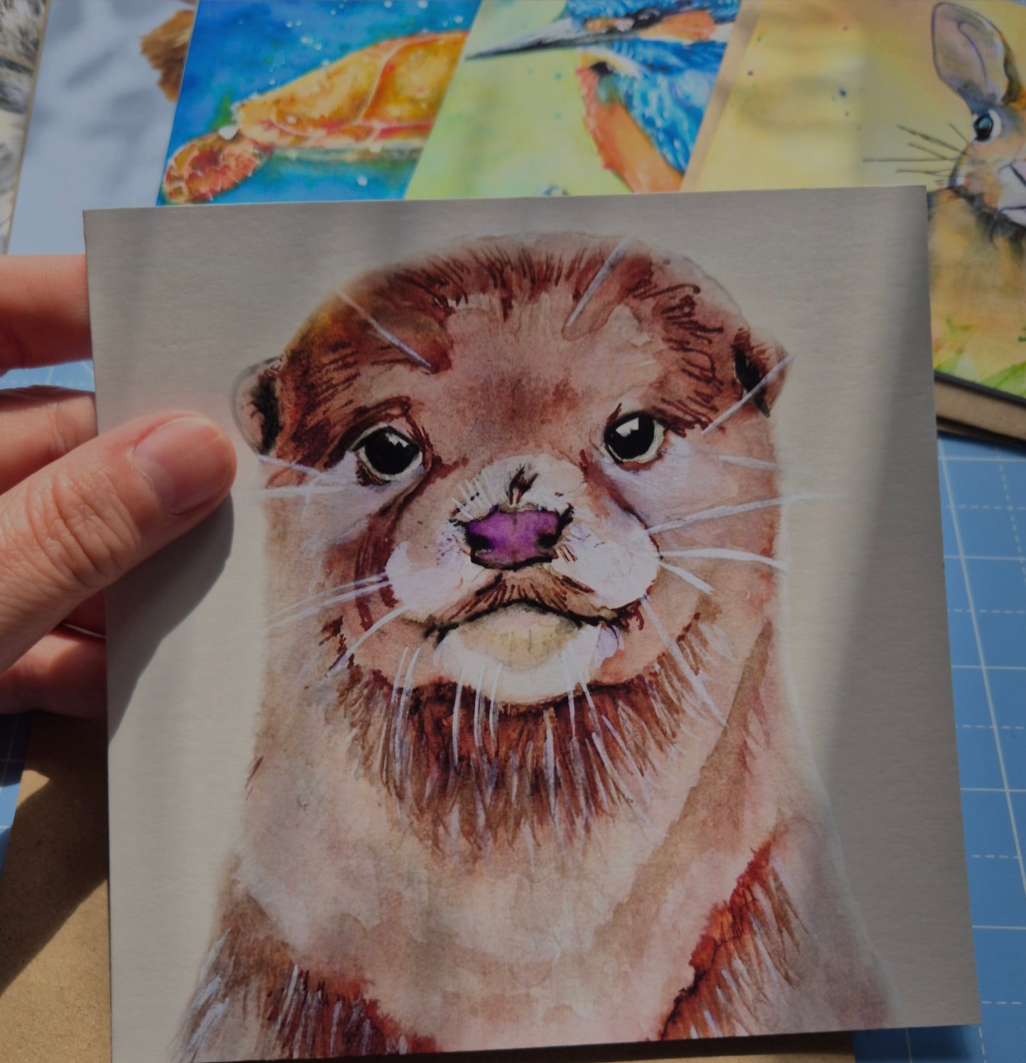 Otter greeting card with animal illustration by Jagos Art held in hand