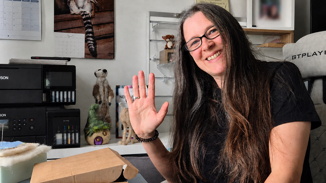 Justine from Felted Woolly Delights smiling and waving from her needle-felting workspace