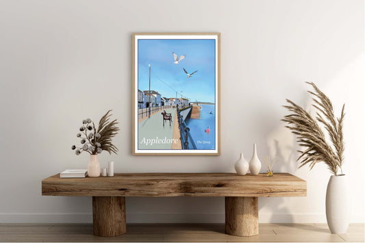 An art print by Jagos Art featuring a print of Appledore Quay in North Devon showing blue sky, the blue river, the buildings, a kayak and some seagulls in flight