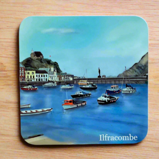Ilfracombe Harbour coaster with boats, harbour shops, a church on the hill, verity statue, blue sea and blue sky