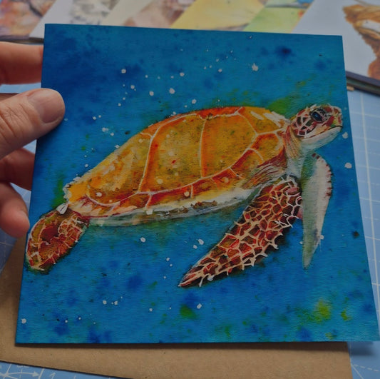 Sea Turtle square greeting card with vibrant  blue background  held in hand
