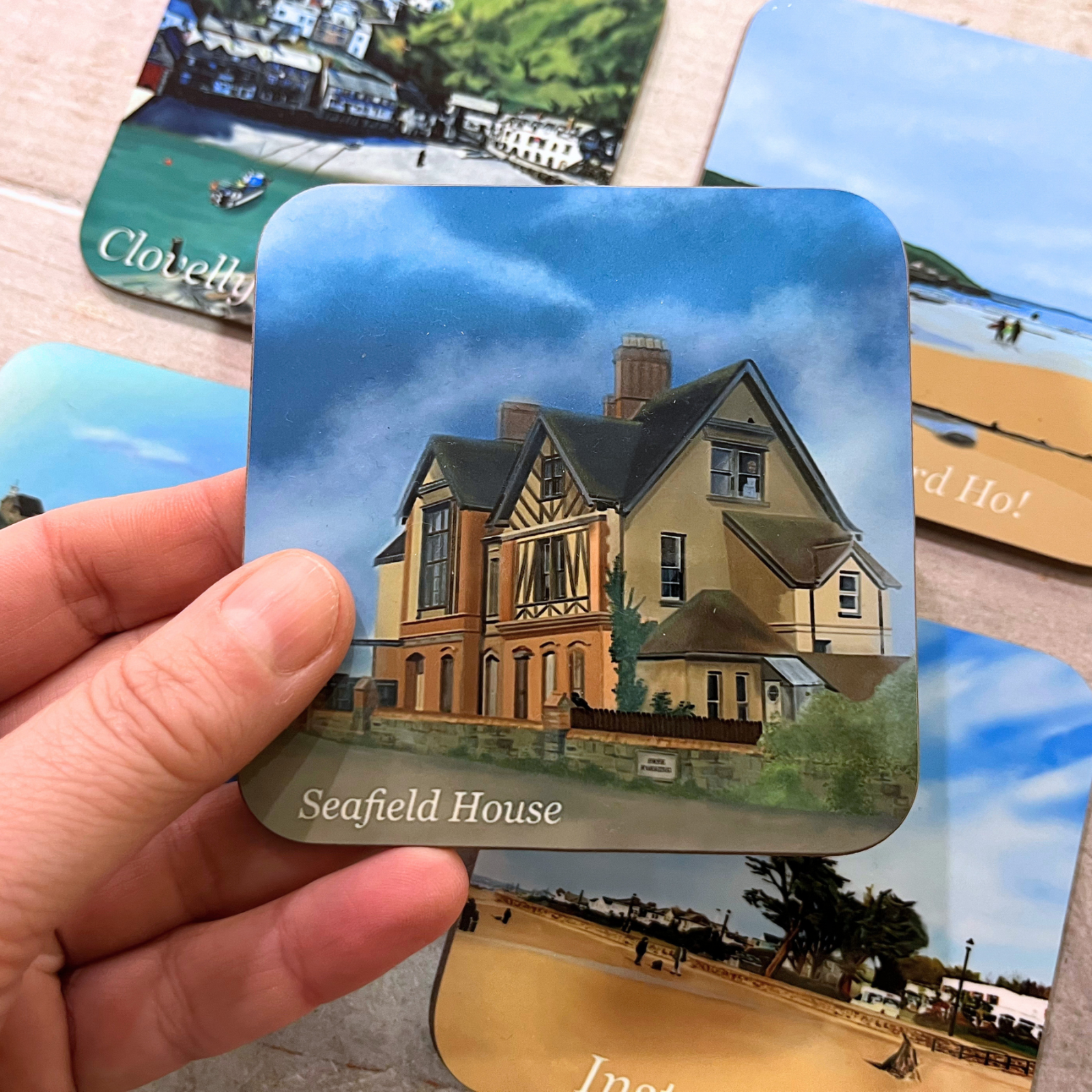 Seafield House and cloudy skies coaster by Jagos Art held in hand