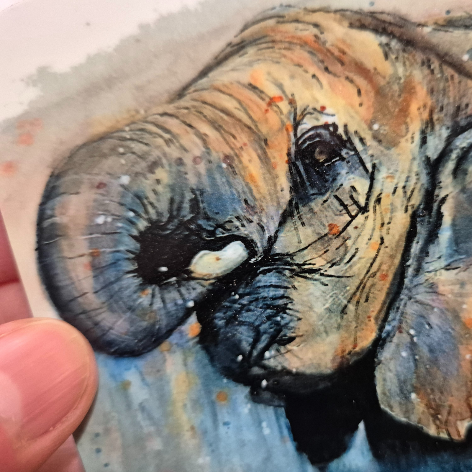 A close up of a hand-painted watercolour elephant coaster, featuring a detailed wildlife illustration printed onto a glossy, cork-backed coaster. The coaster is handmade and heat-resistant, perfect for home décor and gifting.