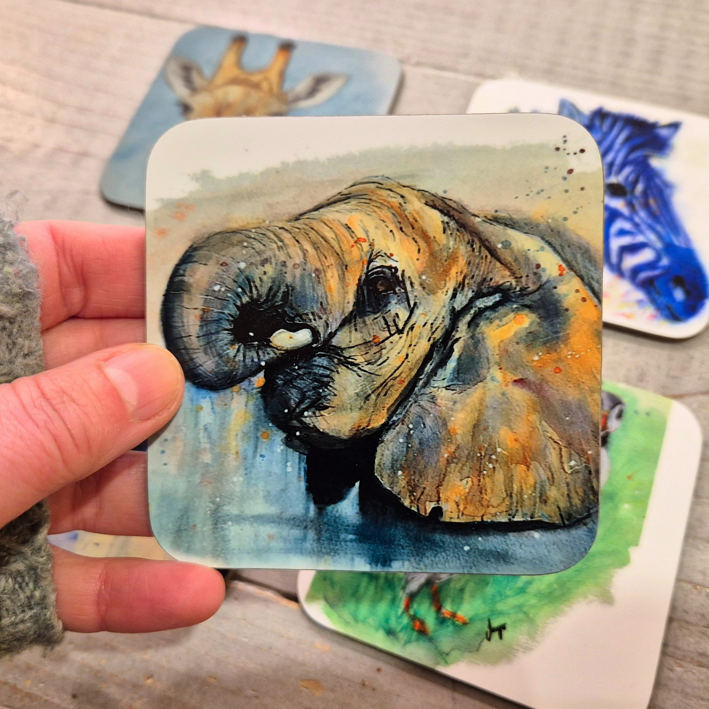 A hand-painted watercolour elephant coaster, featuring a detailed wildlife illustration printed onto a glossy, cork-backed coaster. The coaster is handmade and heat-resistant, perfect for home décor and gifting.