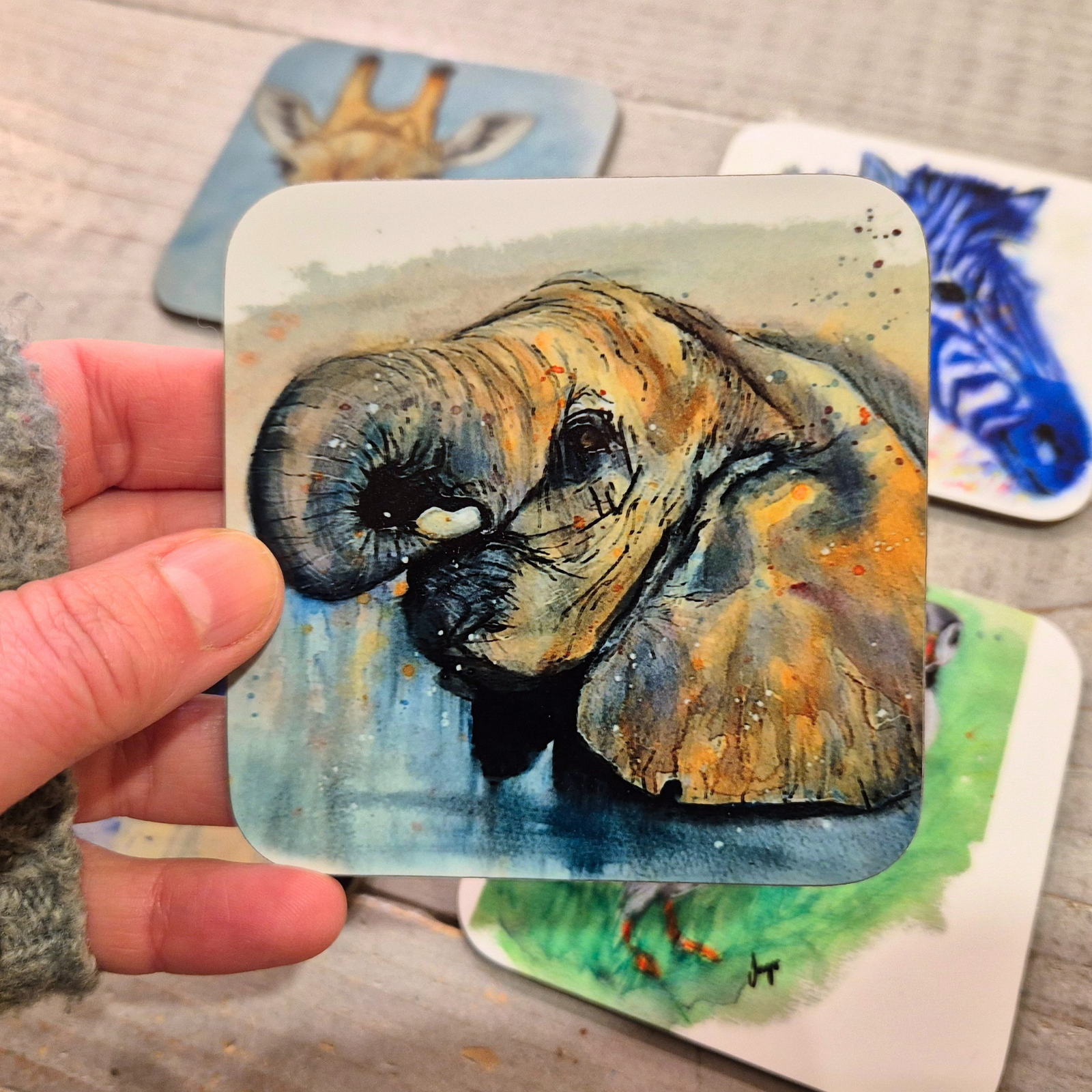 A hand-painted watercolour elephant coaster, featuring a detailed wildlife illustration printed onto a glossy, cork-backed coaster. The coaster is handmade and heat-resistant, perfect for home décor and gifting.