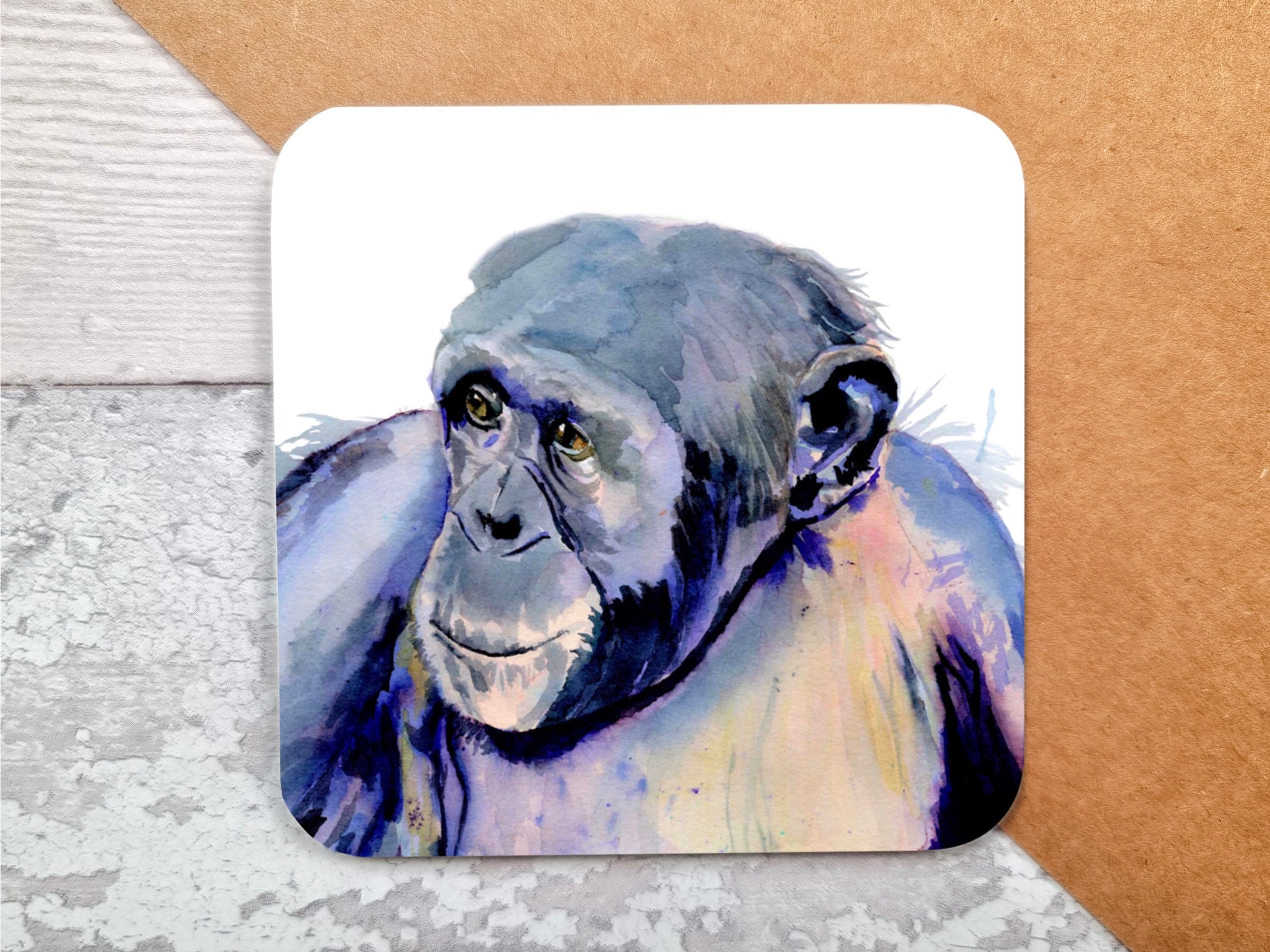 A table coaster handmade by Jagos Art featuring a print of an original watercolour painting by Jagos Art of a Chimpanzee looking at something in the distance with a lovely expression in his eyes painted in primarily purple tones