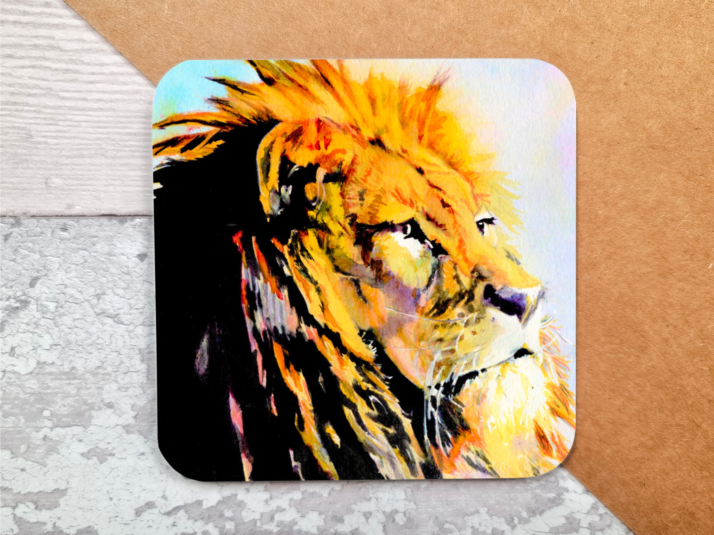 A coaster featuring a print of an original watercolour painting of a stunning Lion with a majestic look on his face and a golden mane primary colours being tones of yellow and orange