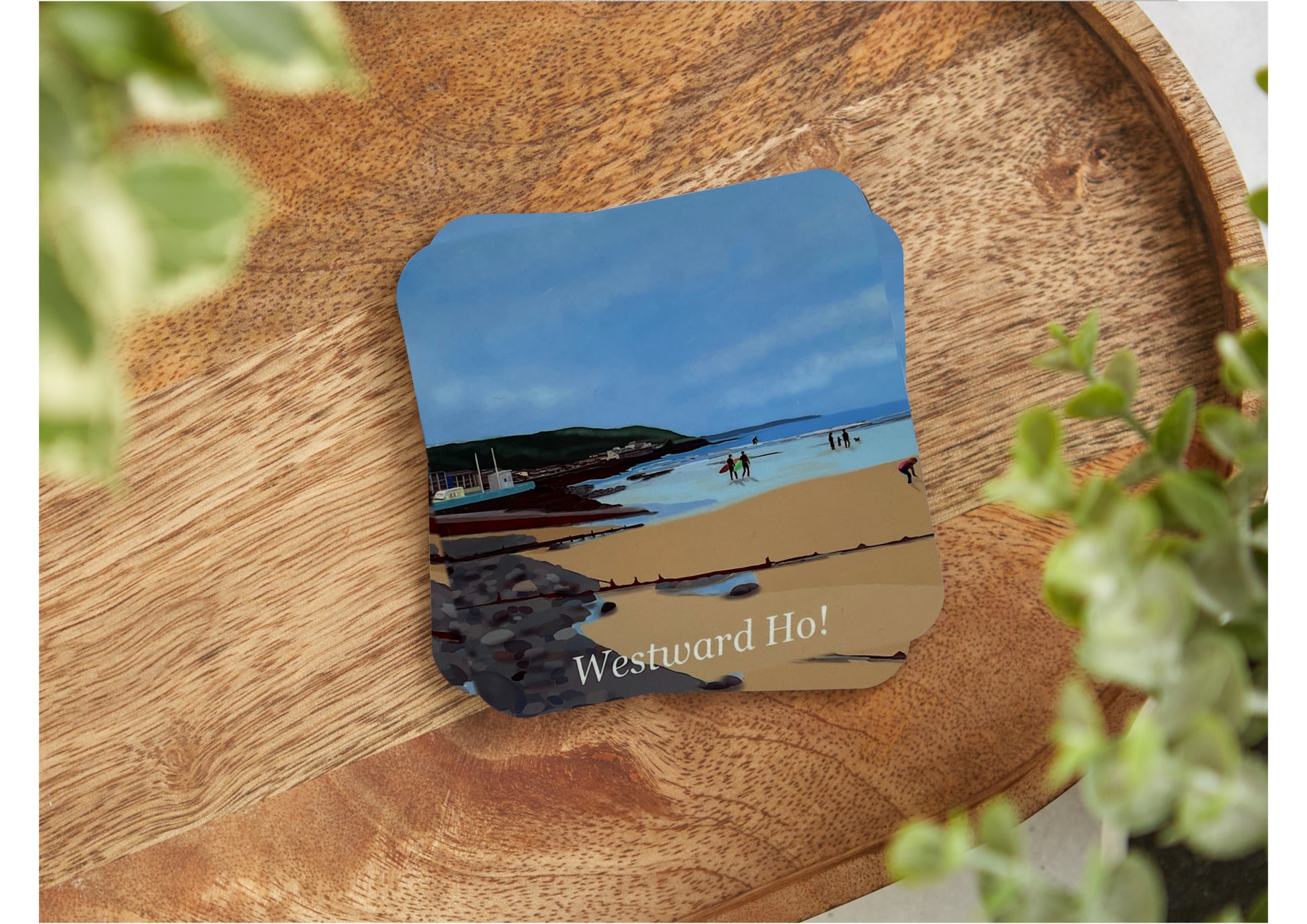 A table coaster featuring a print of Westward Ho Beach looking from the pebbleridge to the slipway with a Hockings van shown and the cliffs in the distance