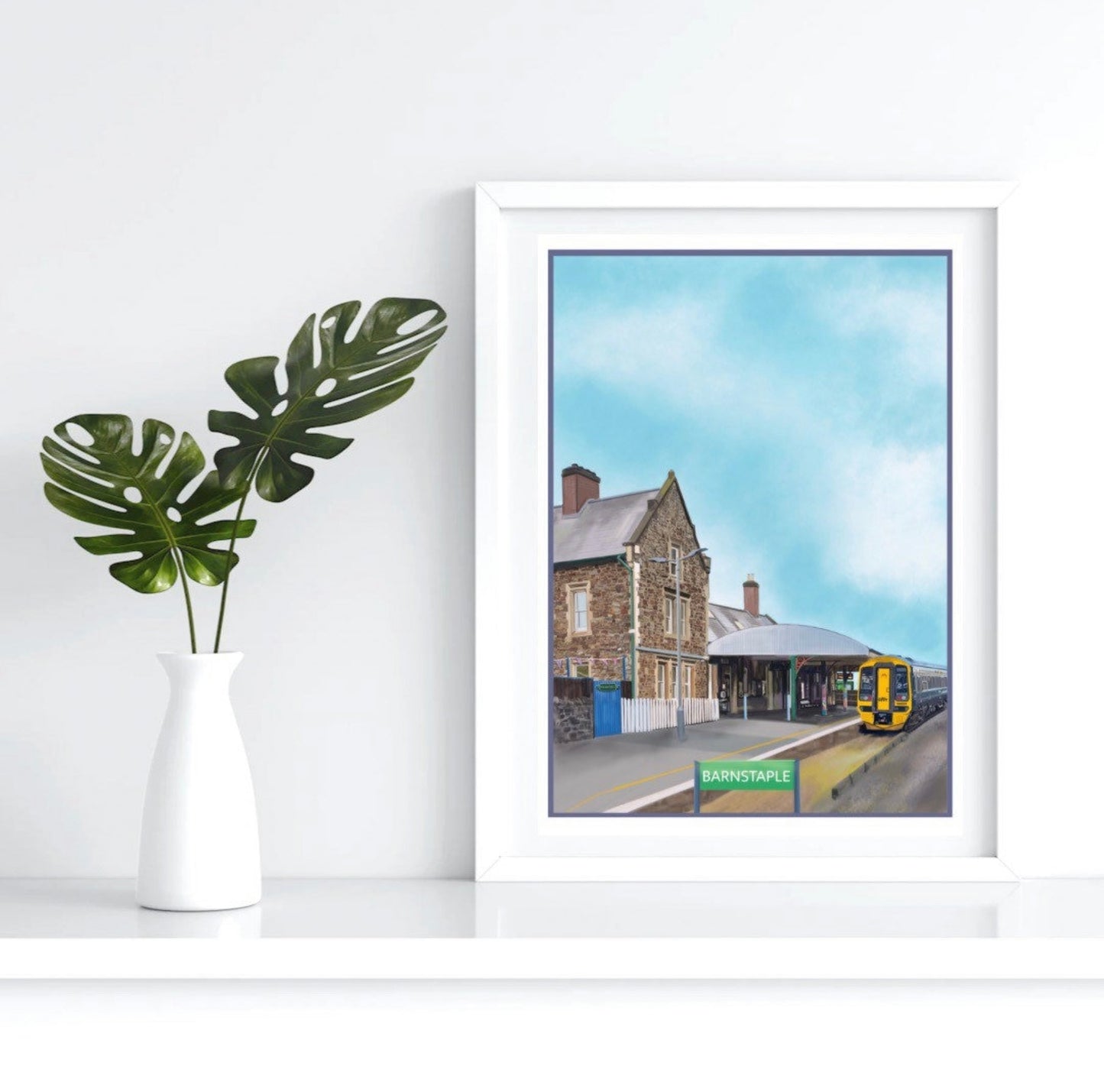 An art print by Jagos Art of Barnstple Train Station in North Devon showing the station masters cafe house, the platform and a train arriving into the station