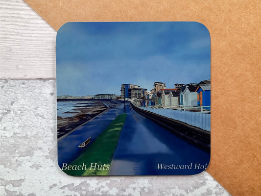 A table coaster handmade by Jagos Art featuring a print by Jagos Art of Westward Ho in North Devon showing the walkway by the sea, the beach huts and some of the village in the distance