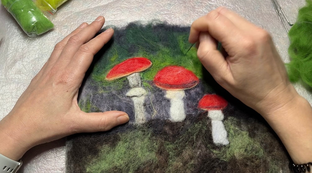 Hands creating a needle-felted mushroom picture for Felted Woolly Delights