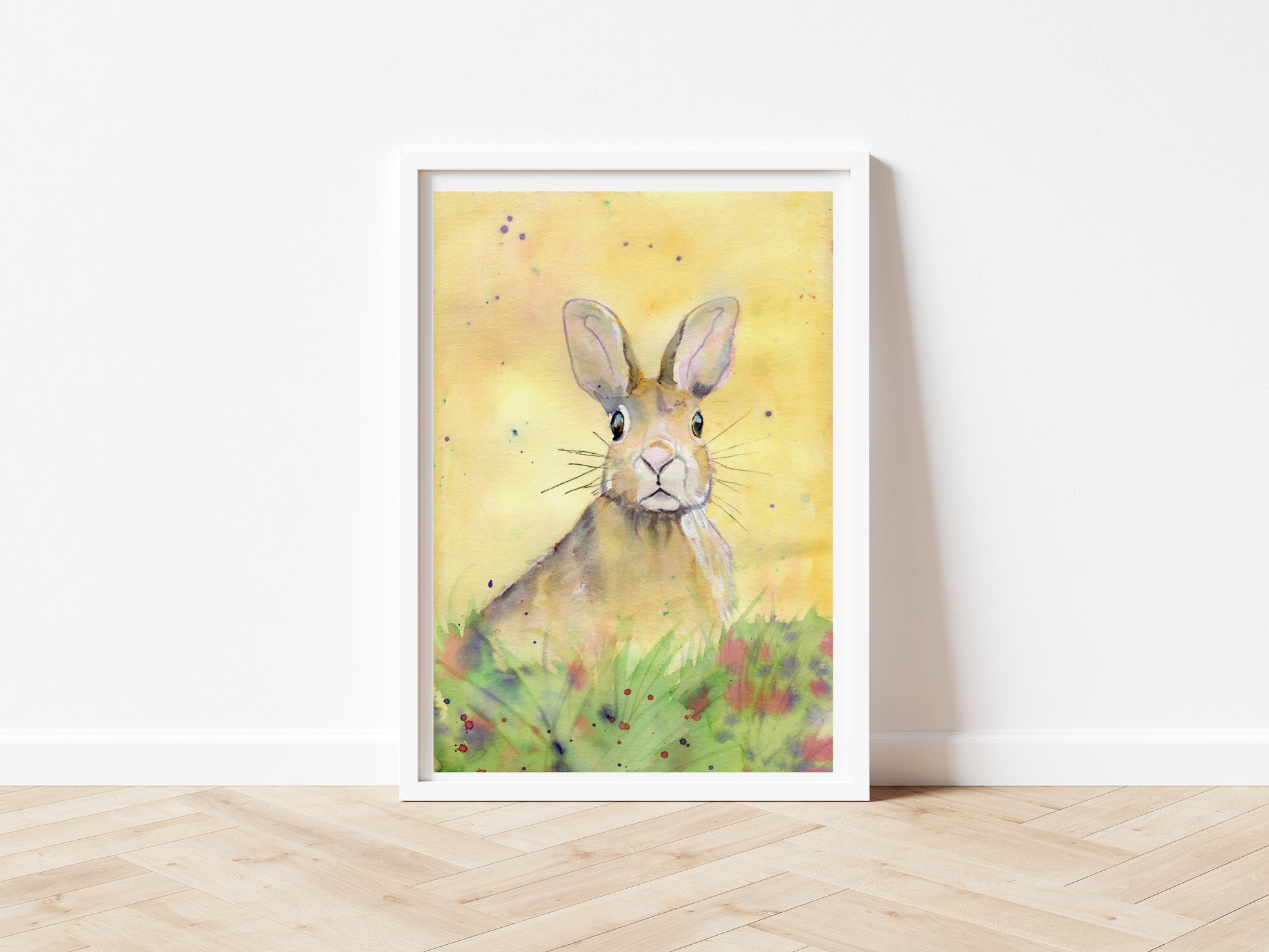 An art print of an original watercolour painting by Jagos Art of a Hare Bunny sitting in the grass and the flowers with an inquistive look on its face looking right at the viewer with a yellow background