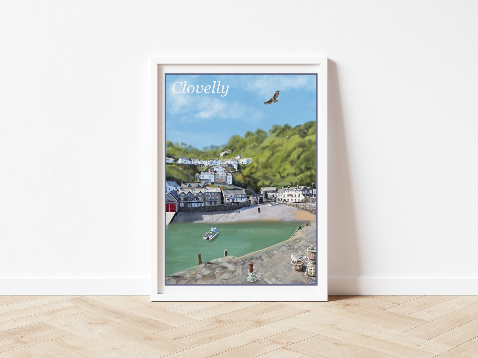 An art print by Jagos Art of the beautiful village of Clovelly in North Devon England showing the harbour with his quaint buildings, the red hotel and the lifeboat station, the small beach and a fishing boat moored with a buzzard flying overhead