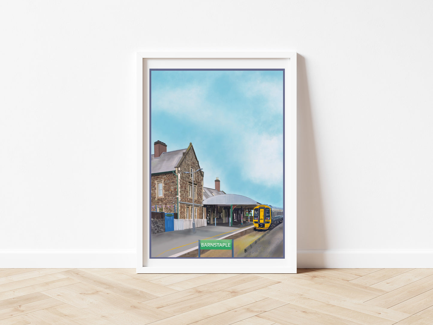 An art print by Jagos Art of Barnstaple Railway Station in North Devon England featuring the Station Masters House Cafe and a train which has arrived at the platform